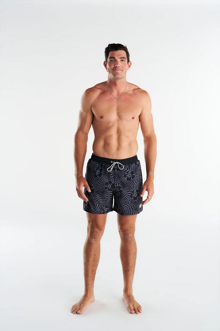 Man wearing black patterned swim shorts on a white background