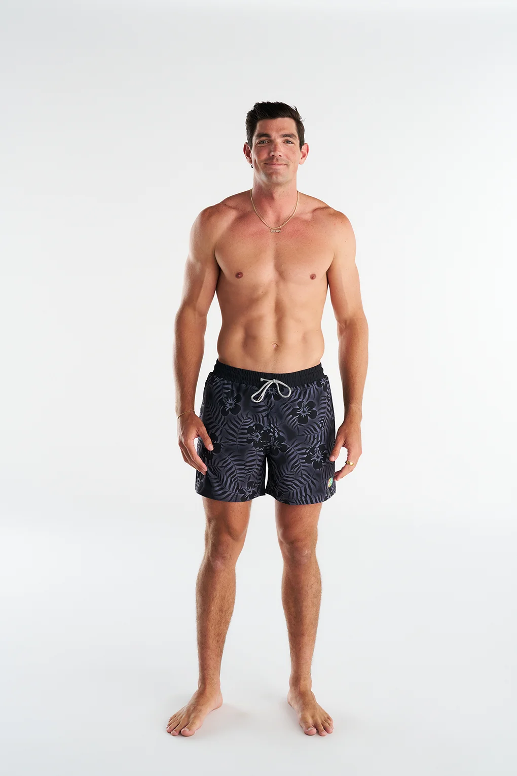 Man wearing black patterned swim shorts on a white background
